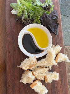 Yin and Yang Dipping Dish Favor with oil and vinegar on a charcuterie board with greens and bread