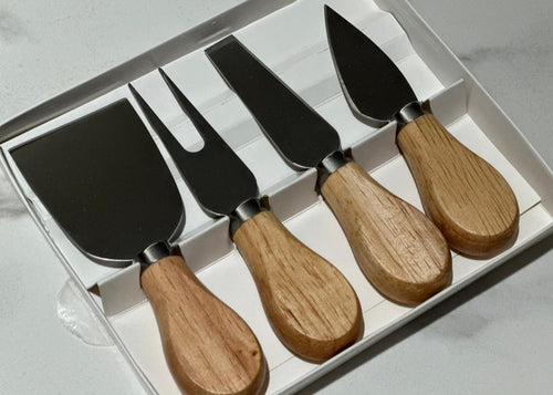Set of four cheese knives with wooden handles in a clear box on a light gray background